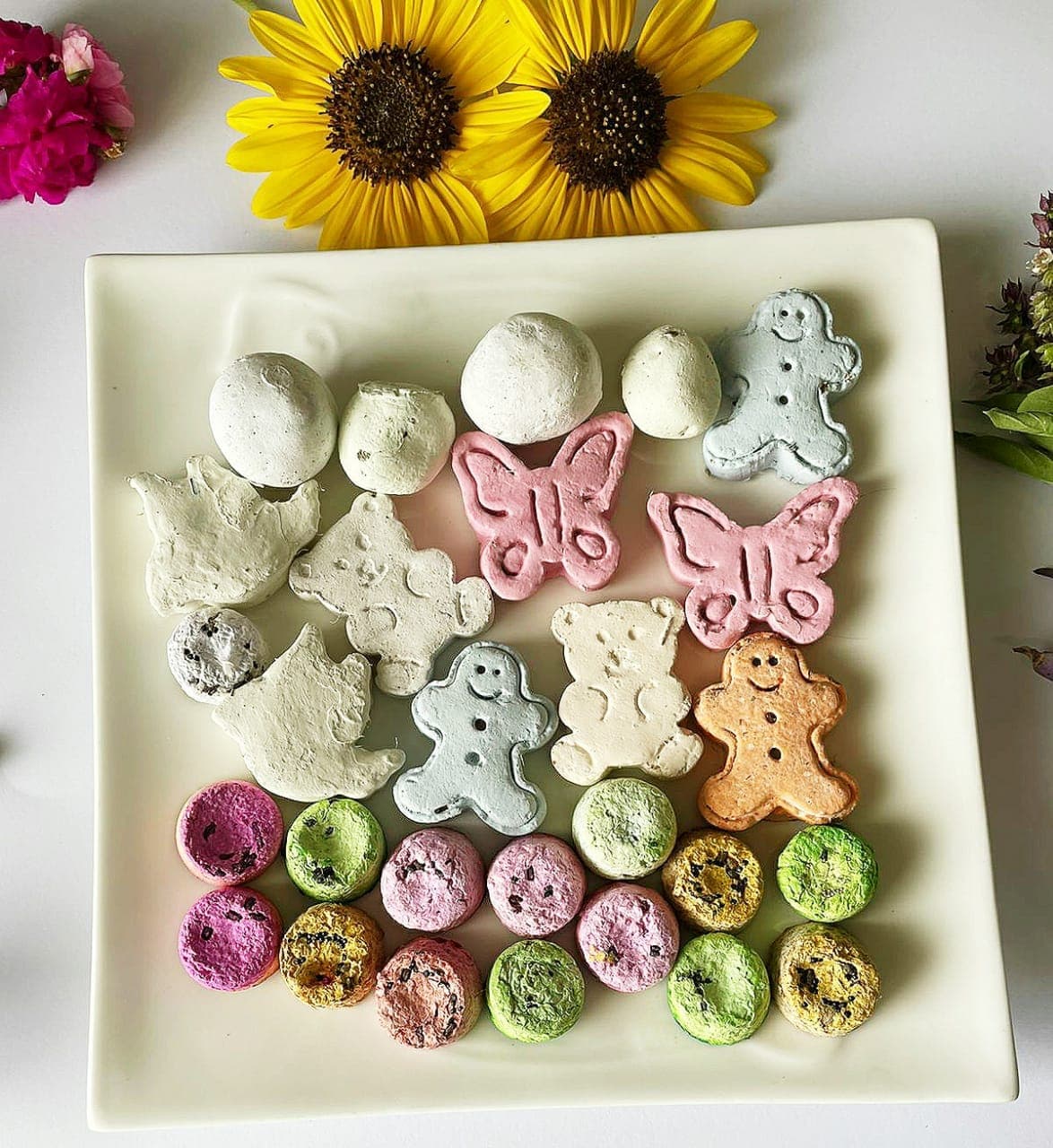 Colorful wildflower seed bombs molded into butterflies, bears and gingerbread shapes on a plate